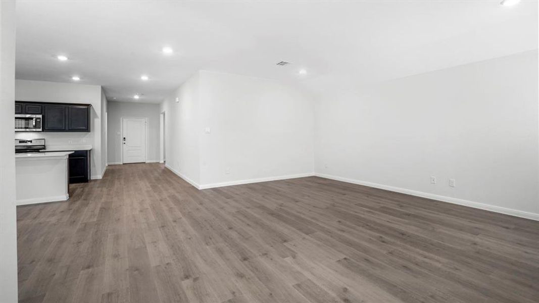 Unfurnished living room featuring recessed lighting and dark wood-type flooring