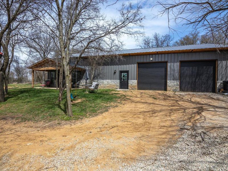 View of front of property featuring an outbuilding, driveway, a garage, board and batten siding, and metal roof