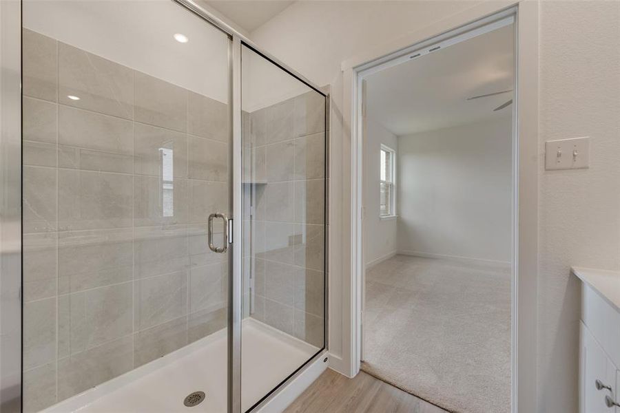 Bathroom featuring wood-type flooring, a shower with door, and vanity