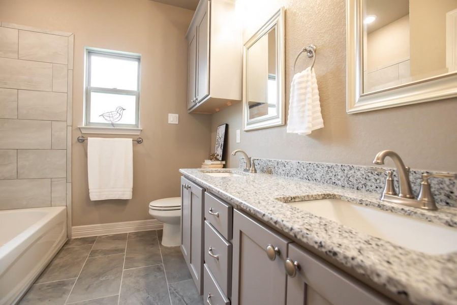 Full bath with a sink, baseboards, toilet, and double vanity