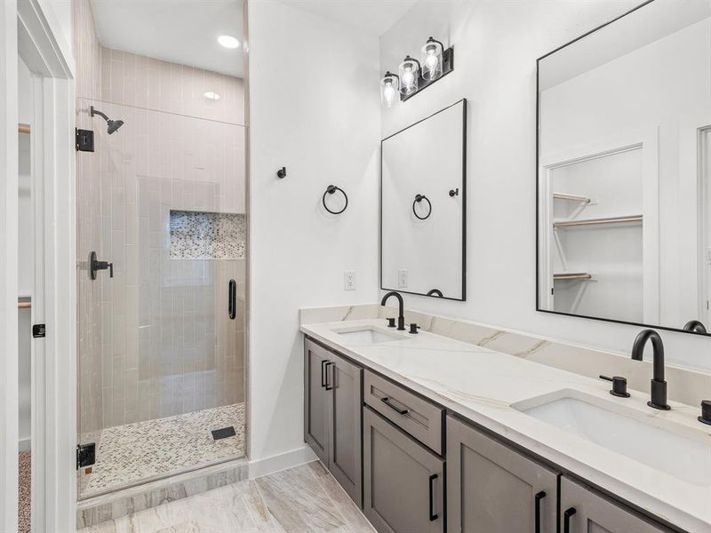 Bathroom featuring a walk in closet, double vanity, a shower stall, and recessed lighting