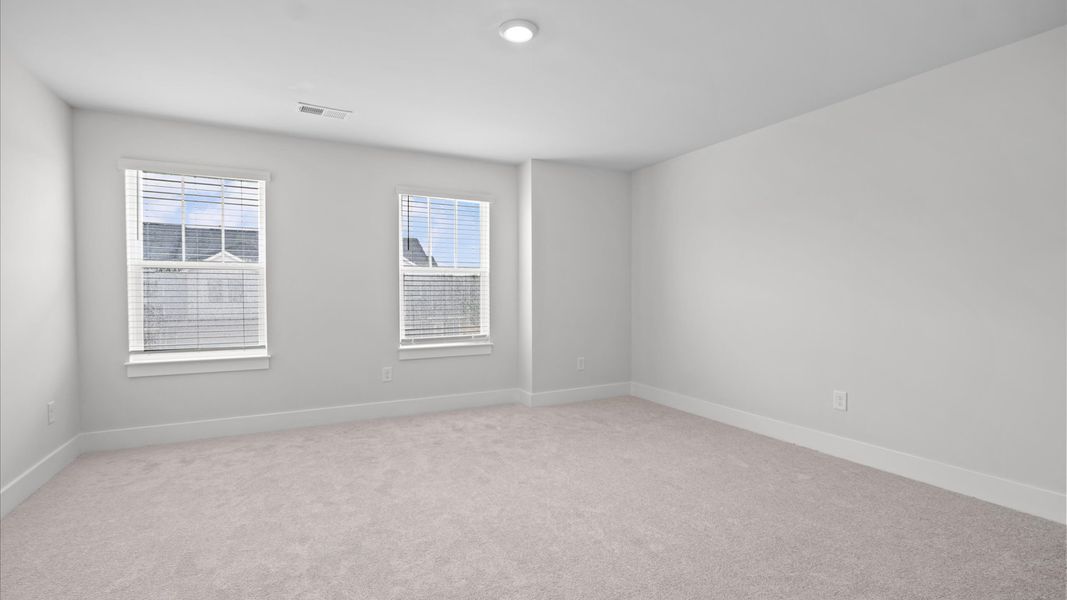 Tasteful secondary bedroom with plush carpet and a spacious walk-in closet at Silo Ridge by DRB Homes in Anderson, SC