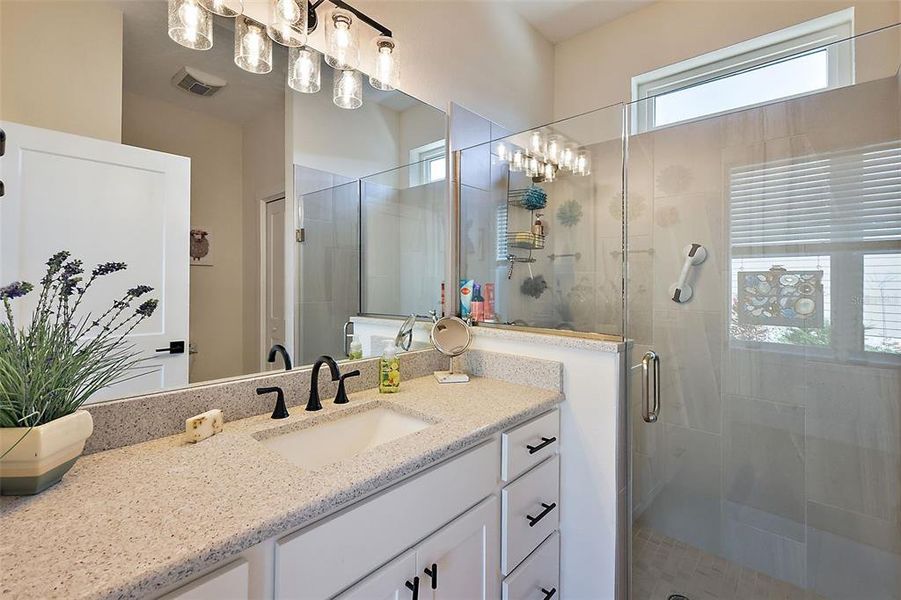 Quartz counter top in the bathroom and tiled walk in shower.