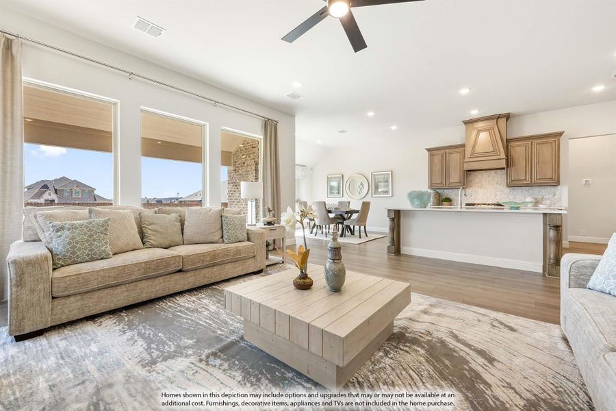Open-concept living room with hardwood floors and ceiling fan, open to kitchen with wood cabinets and breakfast bar Open-concept living room with hardwood floors and ceiling fan, open to kitchen with wood cabinets and breakfast bar