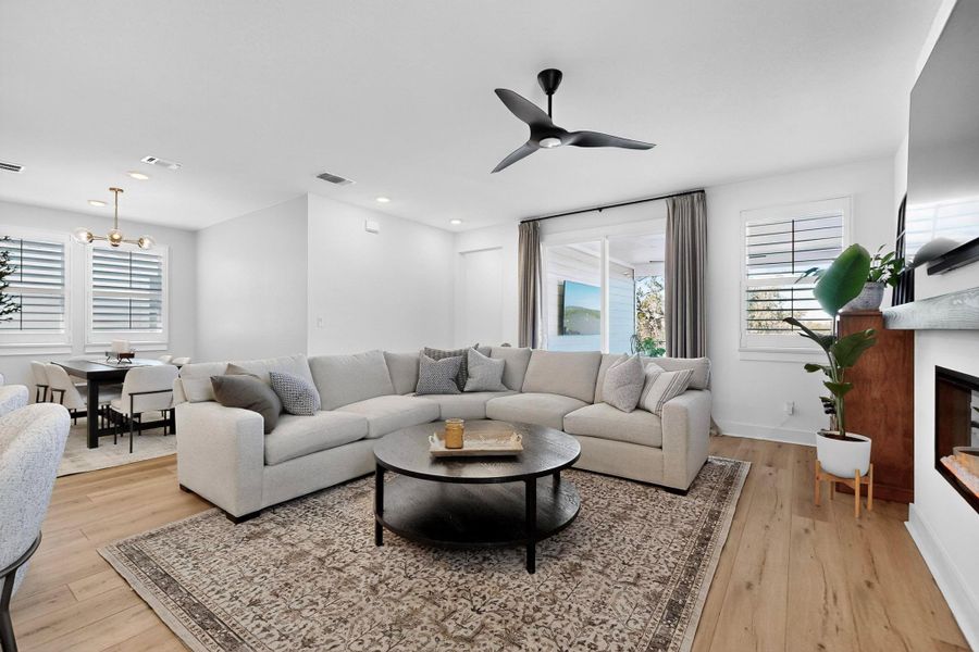 Living room with a glass covered fireplace, plenty of natural light, light wood-style floors, and recessed lighting