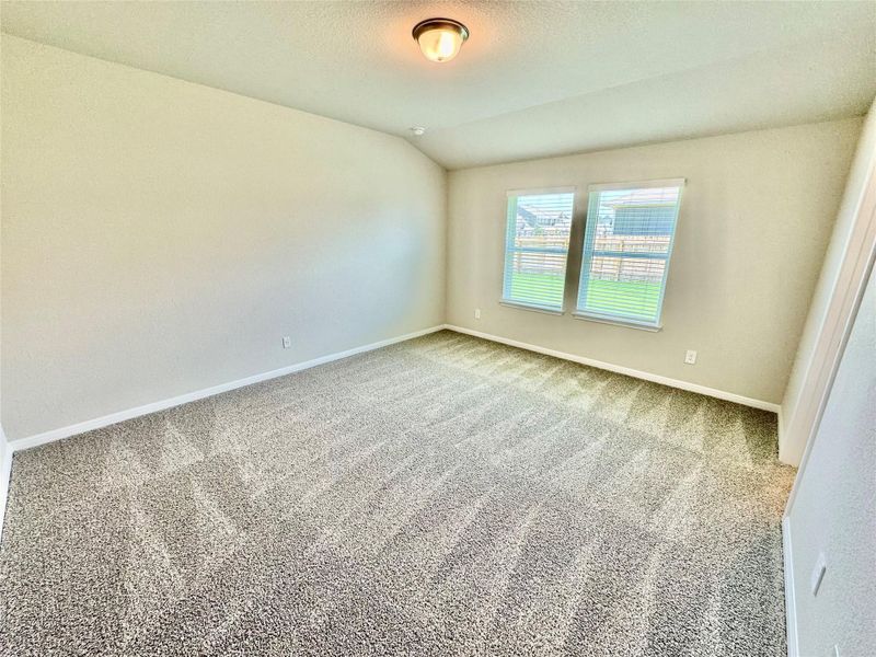 Carpeted empty room featuring vaulted ceiling and baseboards