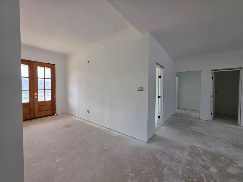 Entryway featuring double wood-paneled doors with clear glass inserts, light-colored walls, and concrete flooring