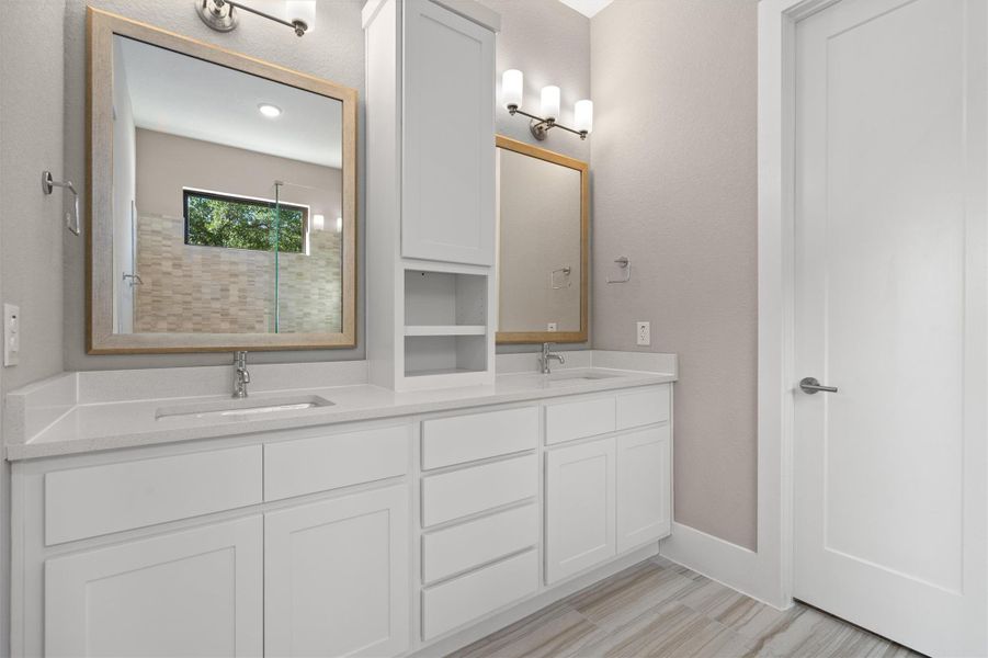 Dual vanities with bright white cabinets and elegant framed mirrors offer ample space. Dual vanities with bright white cabinets and elegant framed mirrors offer ample space.