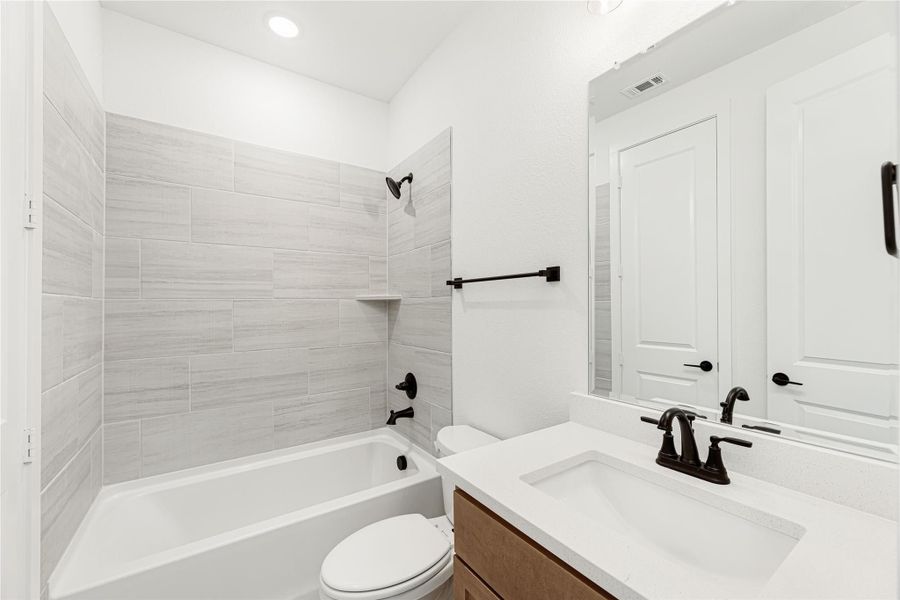 Bathroom with tiled tub-shower combo, white quartz vanity, and dark bronze fixtures Bathroom with tiled tub-shower combo, white quartz vanity, and dark bronze fixtures