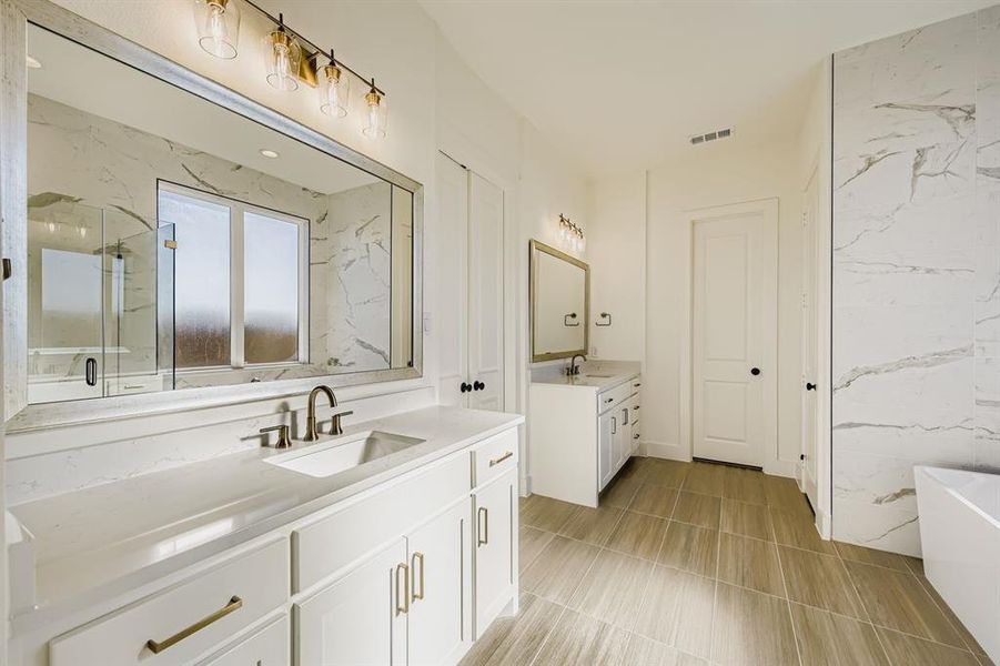 Full bathroom with two vanities, a marble finish shower, and a freestanding tub