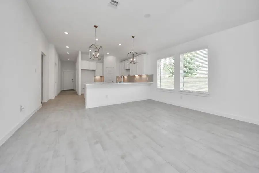 Family room flooded with natural light through the expansive windows.  The premium tile flooring adds a touch of luxury to the space, creating the perfect setting for relaxing moments and cherished gatherings with loved ones. Sample photo of completed home with similar floor plan. Actual colors and selections may vary.