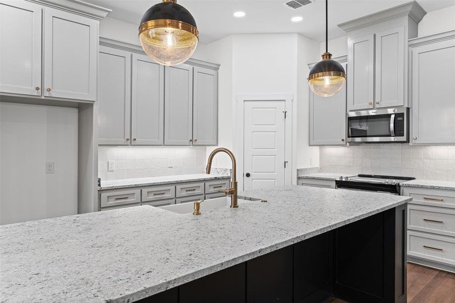 The property features a kitchen with light-colored cabinetry, a large kitchen island with a light-colored countertop, and a built-in microwave