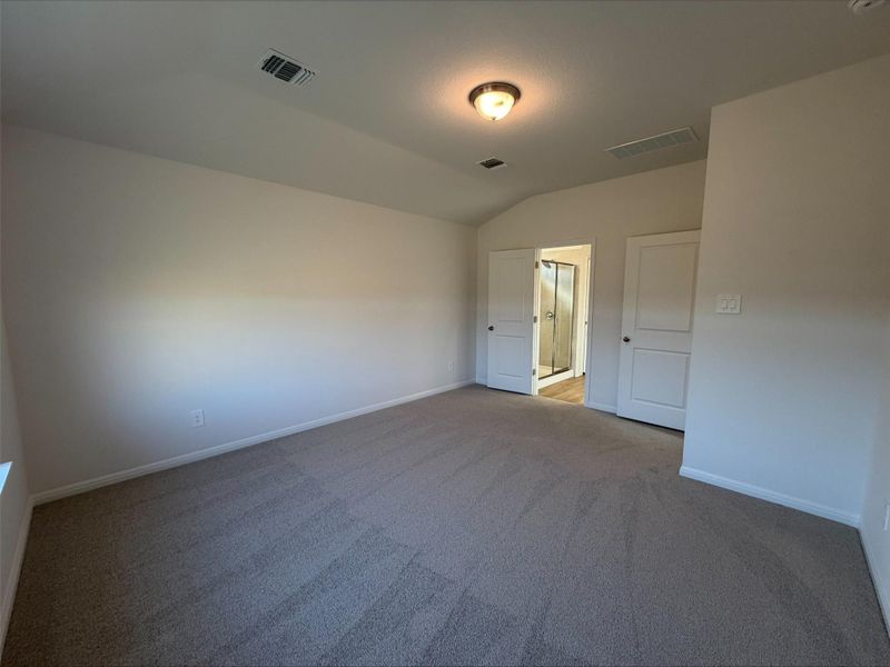 Unfurnished bedroom with vaulted ceiling and carpet flooring