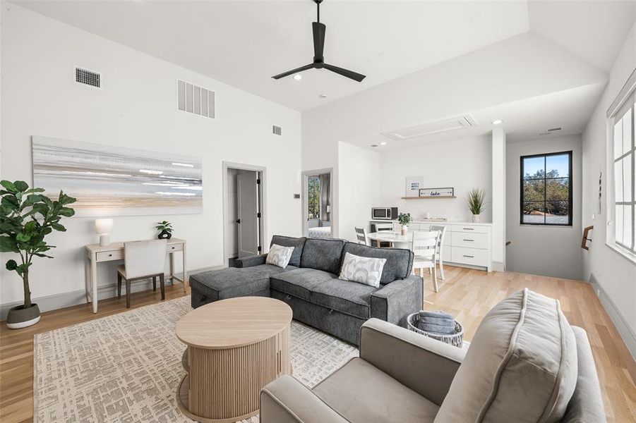 Guest house living and dining and kitchenette area with oak hardwood floors, an office area, ceiling fan, healthy amount of natural light, and a high ceiling