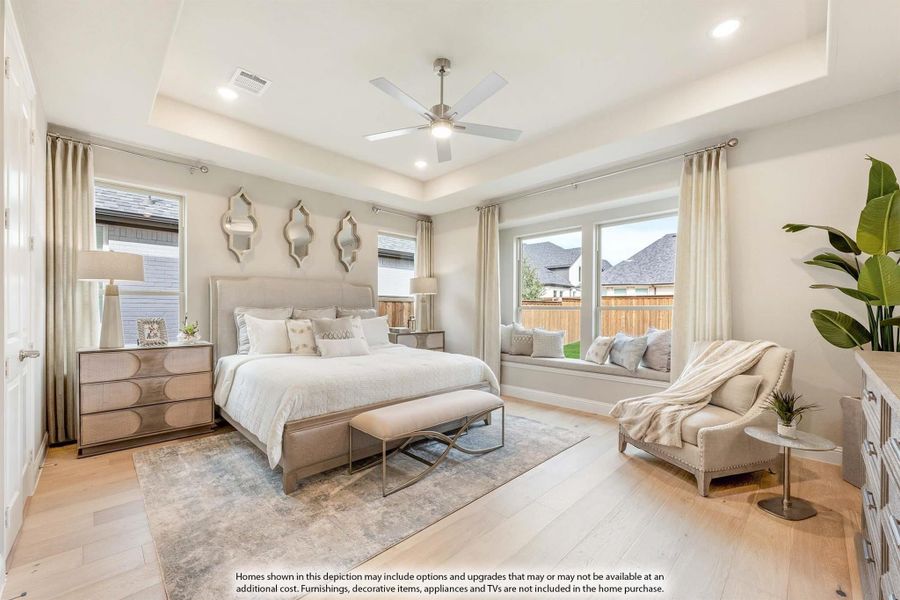 Master bedroom with tray ceiling, ceiling fan, hardwood floors, window seat, and neutral furnishings