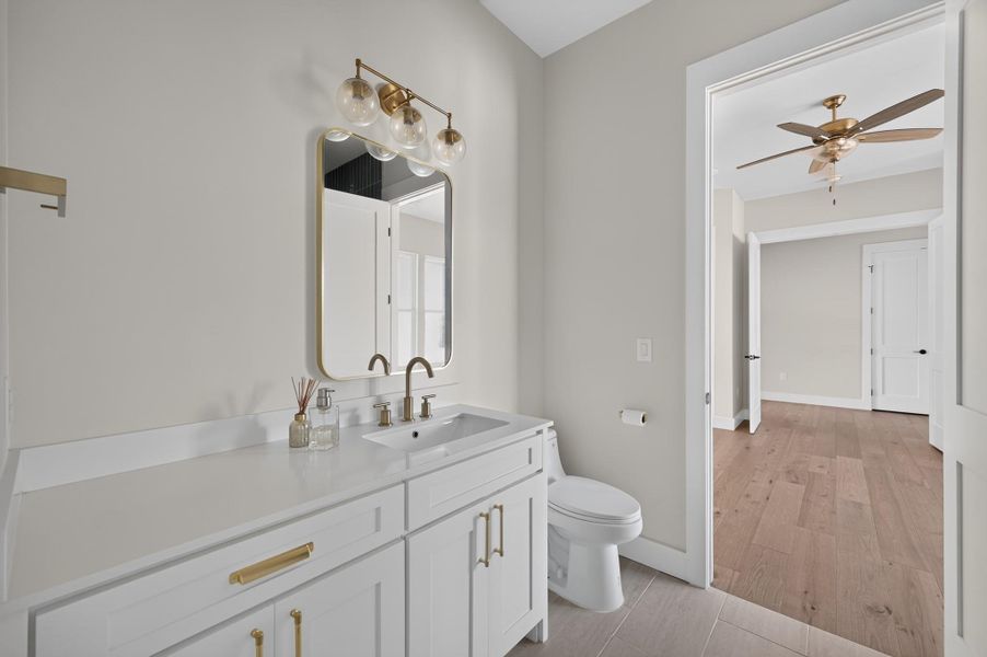 A bright contemporary powder room connects seamlessly to a spacious hallway with wide-plank wood flooring.