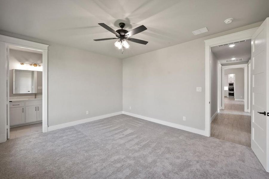 Unfurnished bedroom with ceiling fan, light carpet, and ensuite bathroom