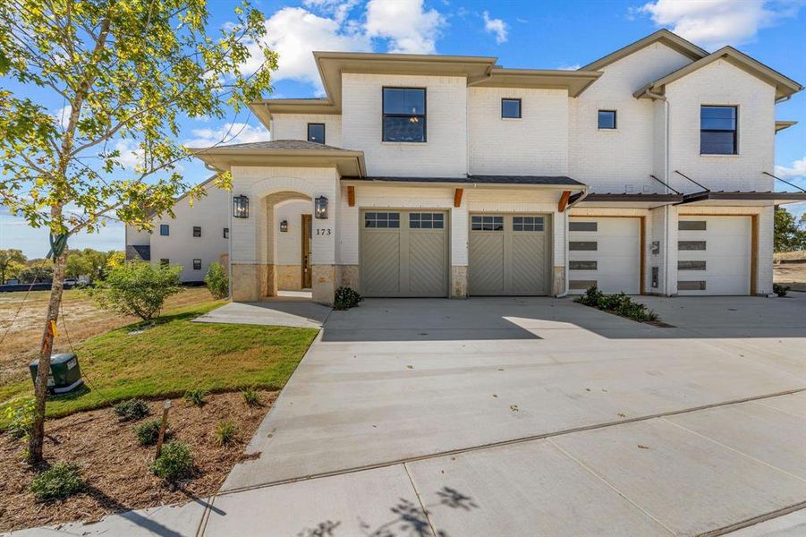 View of front of home featuring an attached garage, brick siding, and concrete driveway
