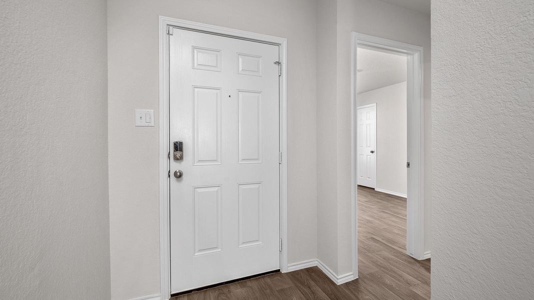 Foyer entrance with a textured wall and dark wood-style flooring