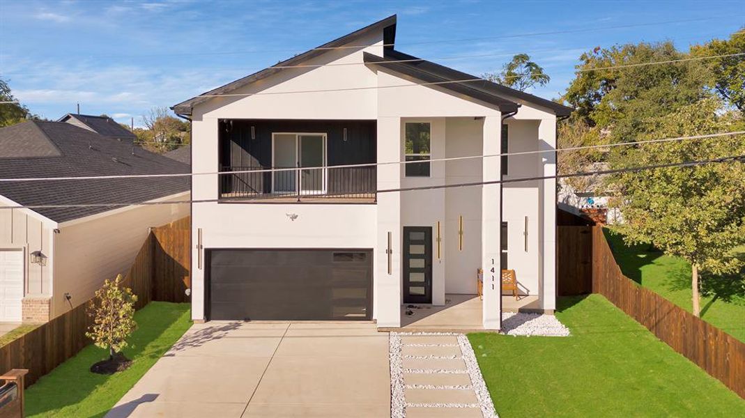 View of front facade featuring a garage and a front lawn