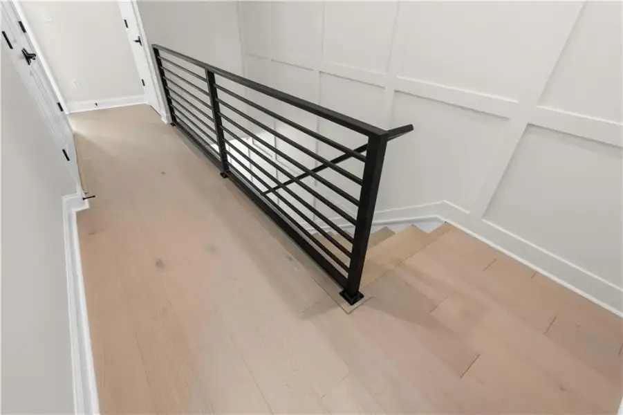 Light wood-finish flooring with a CUSTOM modern black metal railing