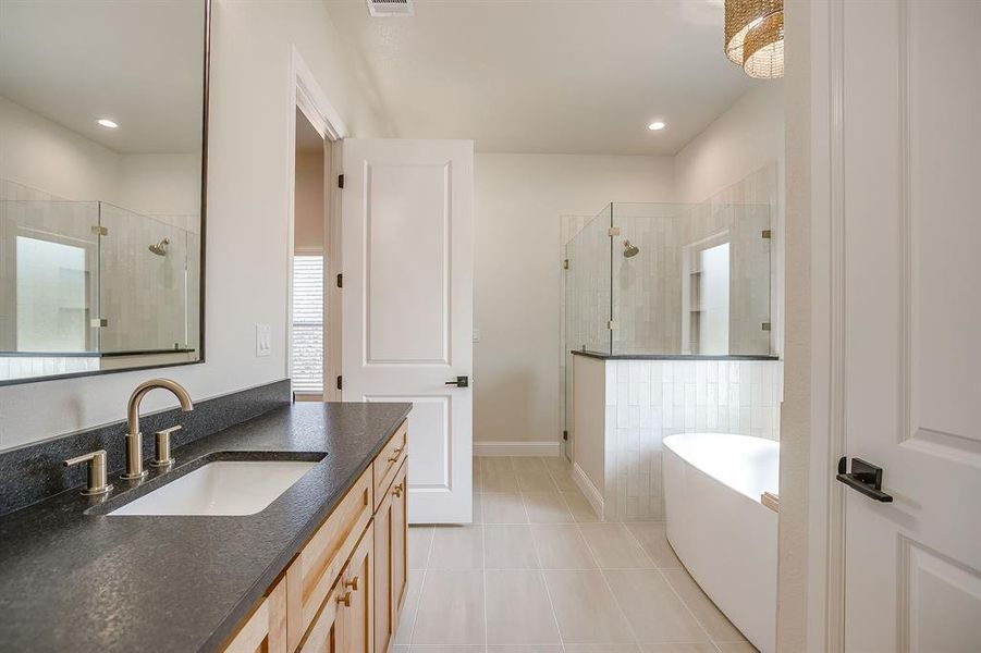 Full bath featuring a stall shower, light tile patterned floors, vanity, and a freestanding tub Full bath featuring a stall shower, light tile patterned floors, vanity, and a freestanding tub