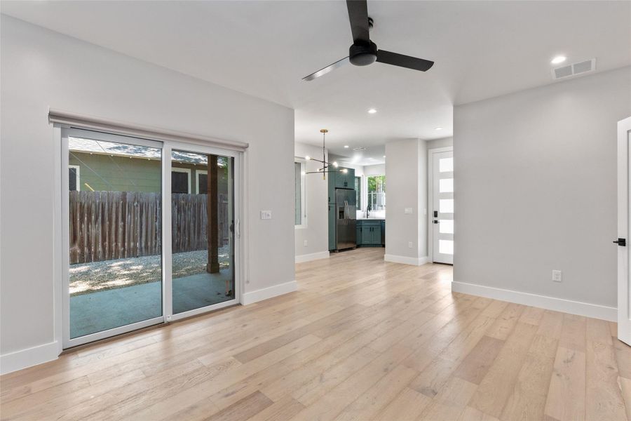 Open-concept living space and dining are with light wood-finish flooring, recessed lighting, and a modern ceiling fan Open-concept living space and dining are with light wood-finish flooring, recessed lighting, and a modern ceiling fan
