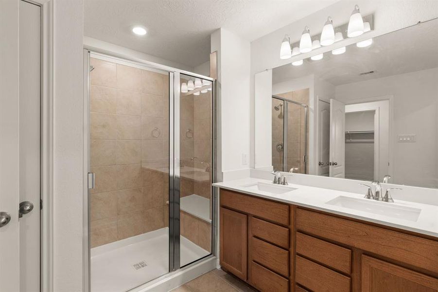 This primary bathroom is definitely move-in ready! Featuring a framed oversized walk-in shower with tile surround, dark stained cabinets with light countertops, spacious walk-in closet with shelving, high ceilings, custom paint, sleek and modern finishes.