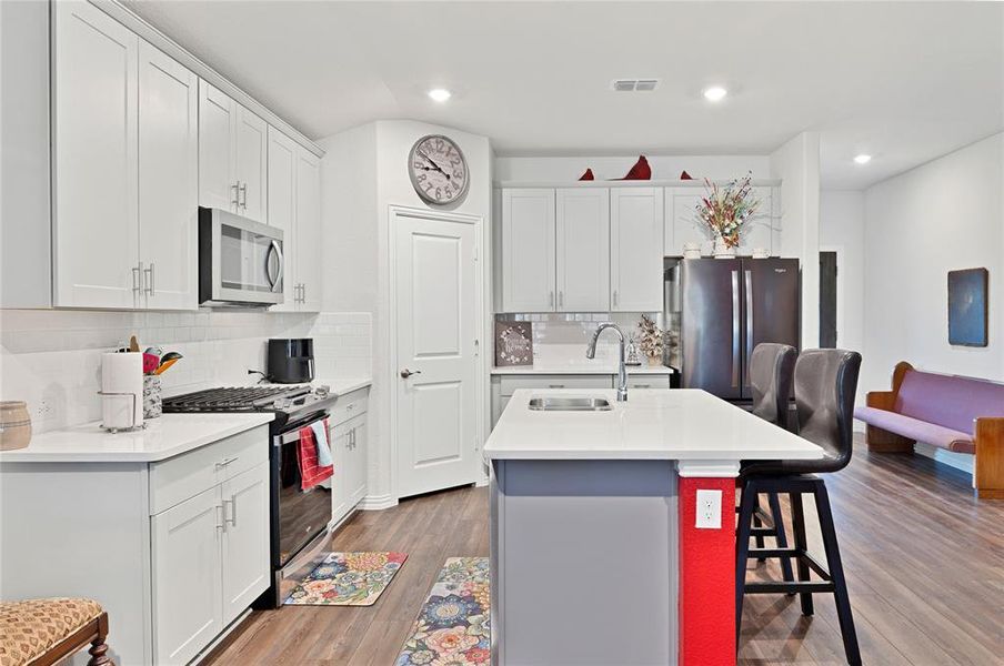 Kitchen with a center island with sink, a breakfast bar area, wood finished floors, stainless steel appliances, and a sink