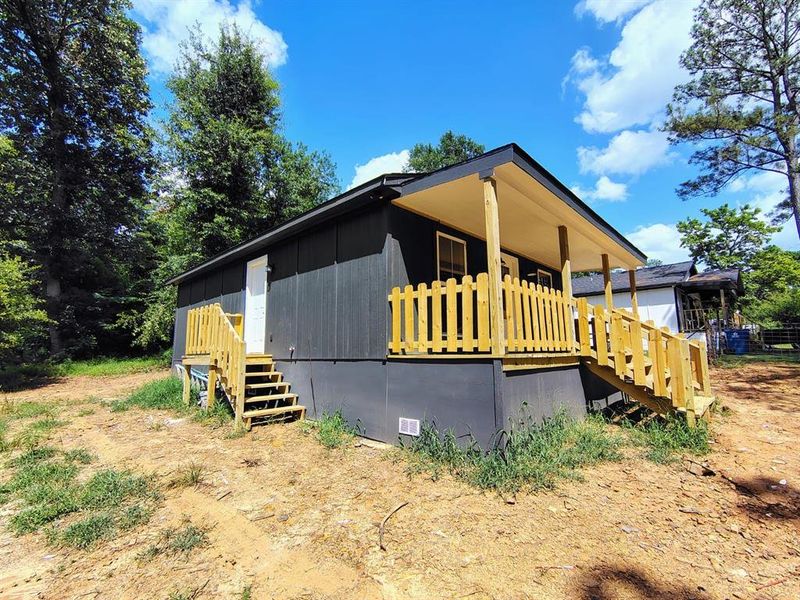 View of side of home with stairs and crawl space