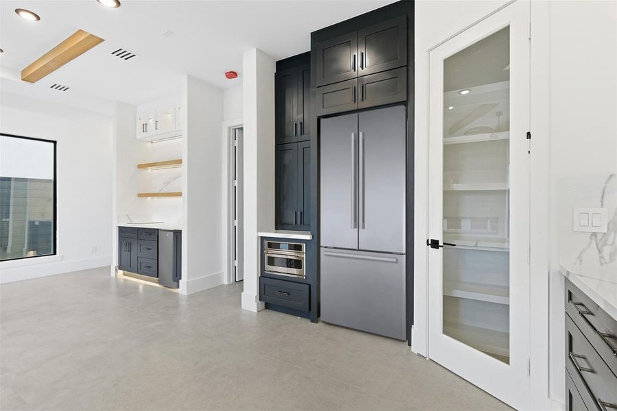 The kitchen includes an integrated refrigerator wall with a microwave drawer and a glass-paneled pantry door.