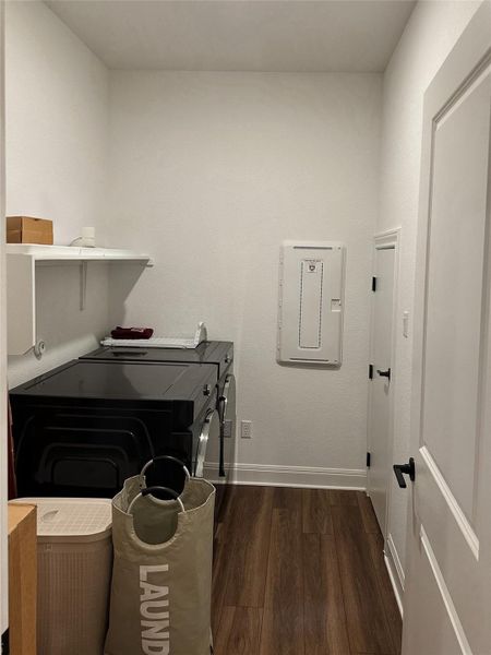 Laundry area featuring wood-finish flooring, white walls, and a built-in floating shelf Laundry area featuring wood-finish flooring, white walls, and a built-in floating shelf