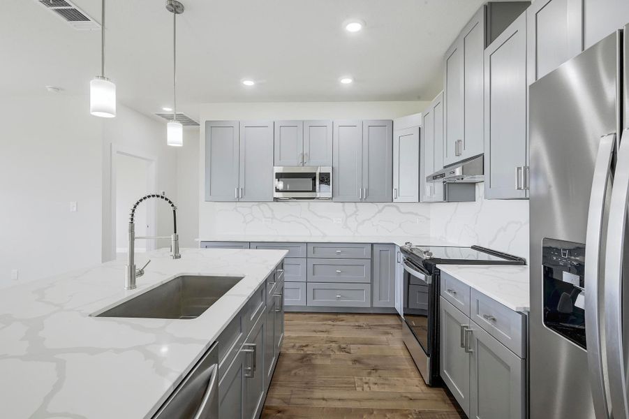 Kitchen with appliances with stainless steel finishes, under cabinet range hood, gray cabinetry, recessed lighting, and dark wood-style floors