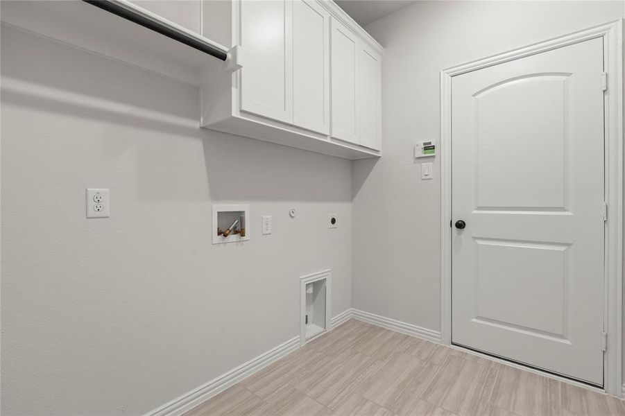 Clothes washing area featuring electric dryer hookup, gas dryer hookup, cabinets, and hookup for a washing machine