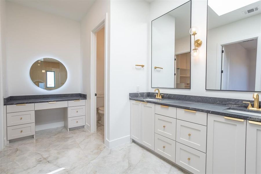 Bathroom with a skylight, vanity, and toilet