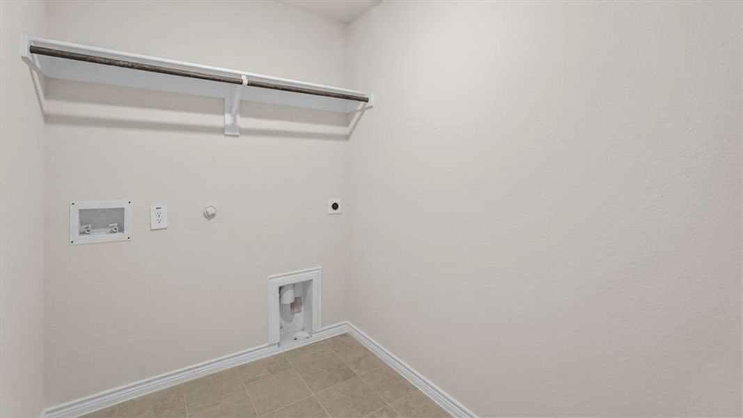 Dedicated laundry space featuring neutral-toned walls, tile flooring, and a built-in hanging rod Dedicated laundry space featuring neutral-toned walls, tile flooring, and a built-in hanging rod