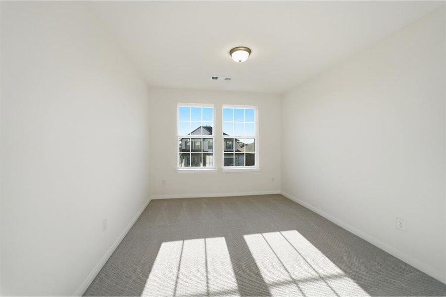 Room featuring two grid-pattern windows, neutral carpet flooring, white walls, and a ceiling-mounted light fixture