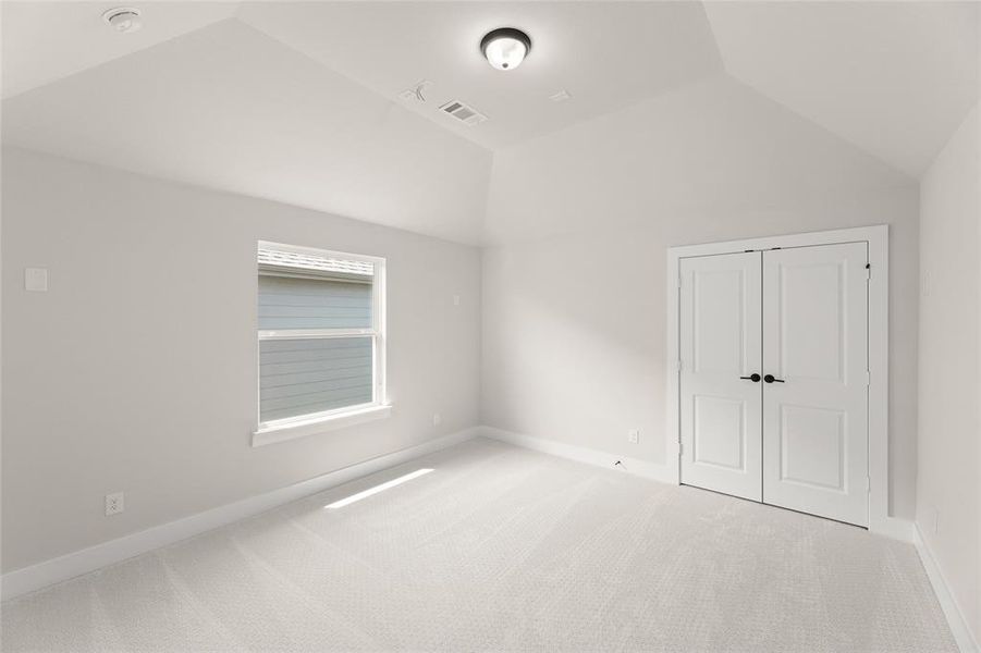Unfurnished bedroom featuring baseboards, a closet, vaulted ceiling, visible vents, and carpet