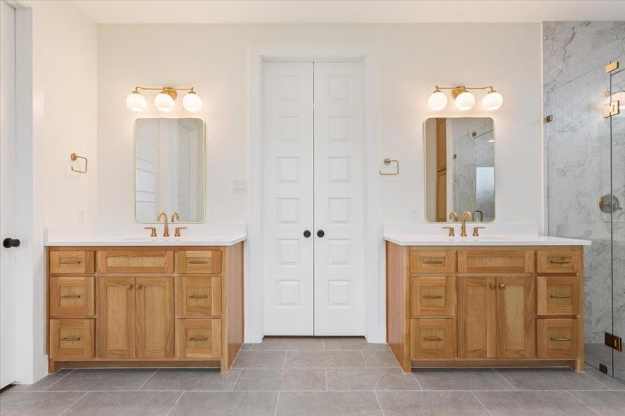 Full bathroom featuring a stall shower, two vanities, and light tile patterned floors