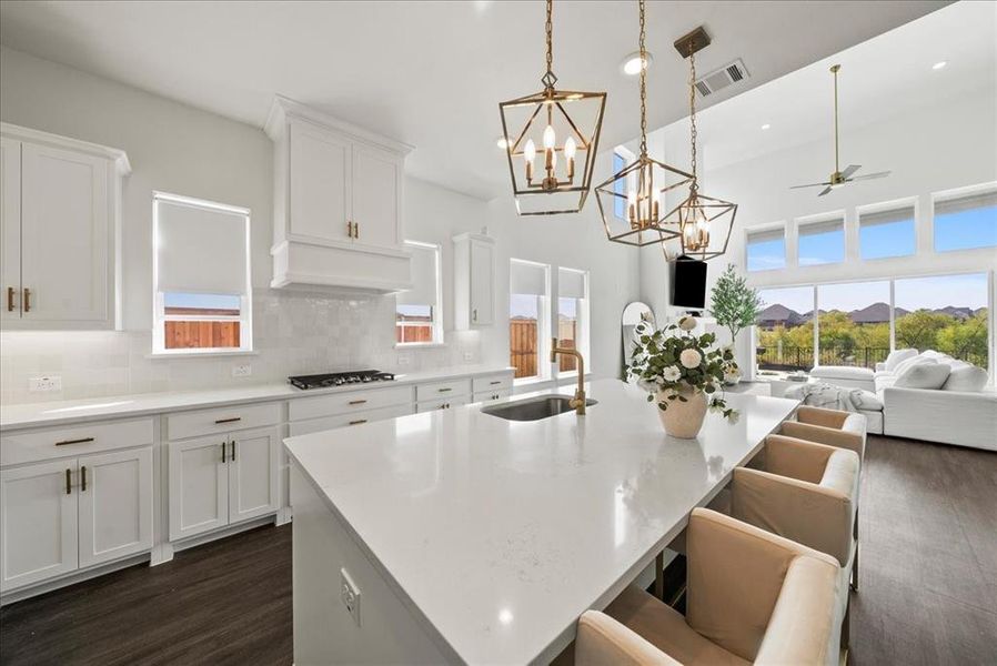 Kitchen with visible vents, decorative backsplash, open floor plan, premium range hood, and a sink