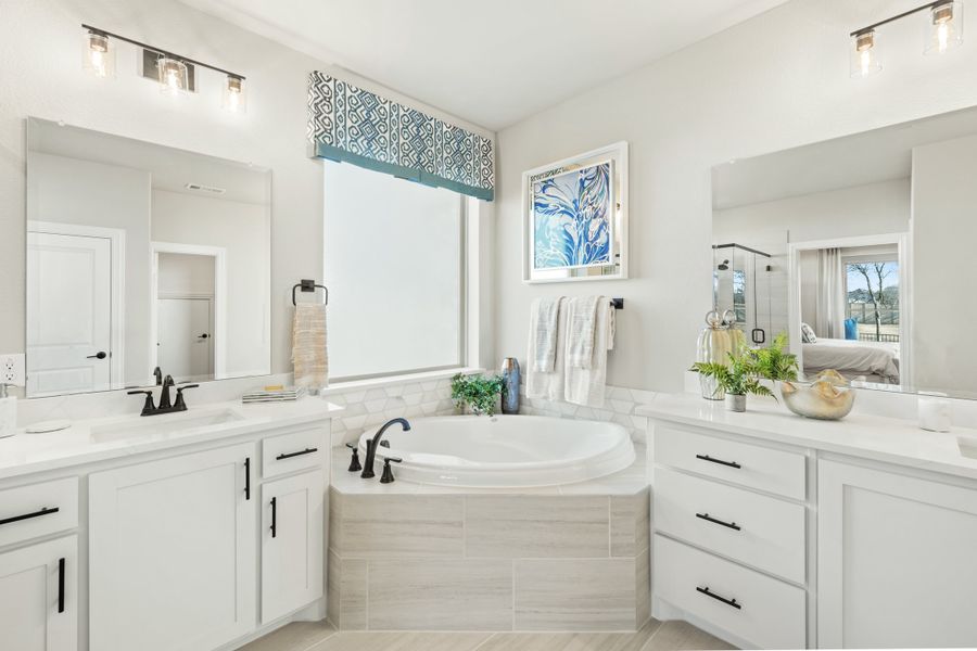 Master bathroom with dual vanities, soaking tub, white cabinets, and black hardware accents Master bathroom with dual vanities, soaking tub, white cabinets, and black hardware accents