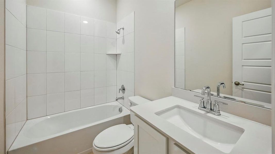 Bathroom featuring a white subway tile shower surround, built-in shower shelf, chrome fixtures, white vanity with integrated sink, and a large mirror