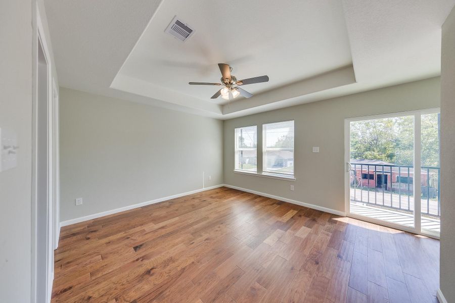 Golden natural light pours into this primary bedroom, creating a warm, cheerful atmosphere to start your mornings off right.