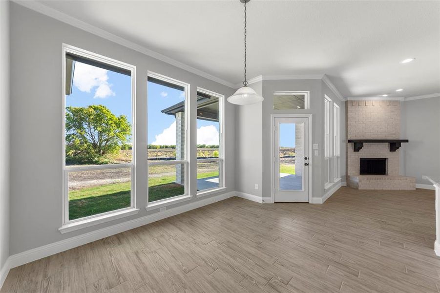 Unfurnished dining area with light wood-type flooring, a healthy amount of sunlight, and a brick fireplace