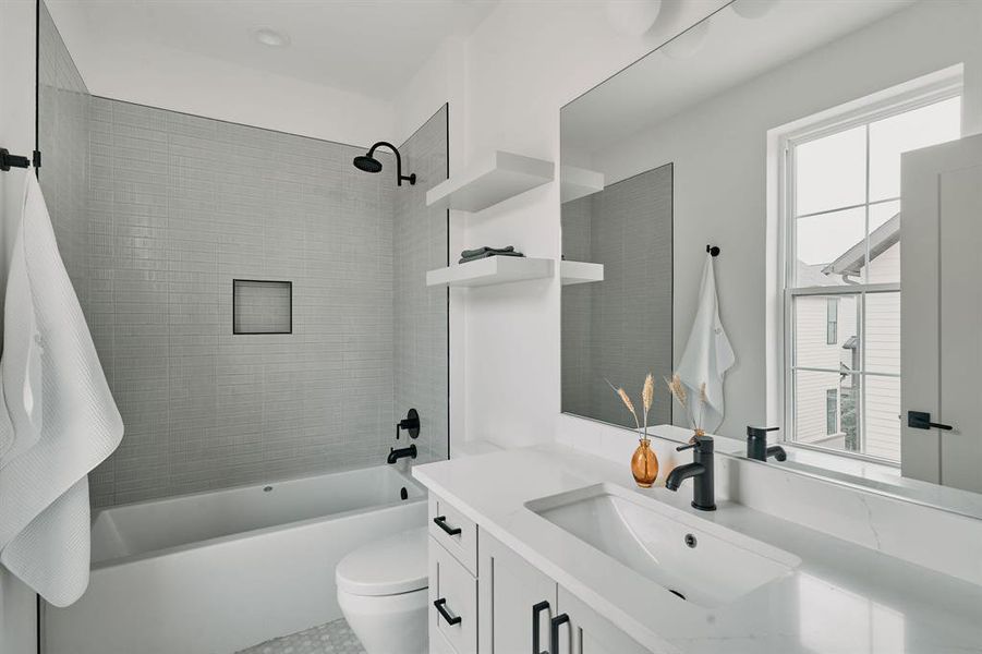 Contemporary bathroom featuring a tub/shower combination with a tiled surround, integrated shower niche, and matte black fixtures Contemporary bathroom featuring a tub/shower combination with a tiled surround, integrated shower niche, and matte black fixtures