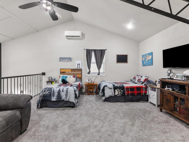 Carpeted bedroom featuring a ceiling fan, vaulted ceiling, and a wall unit AC