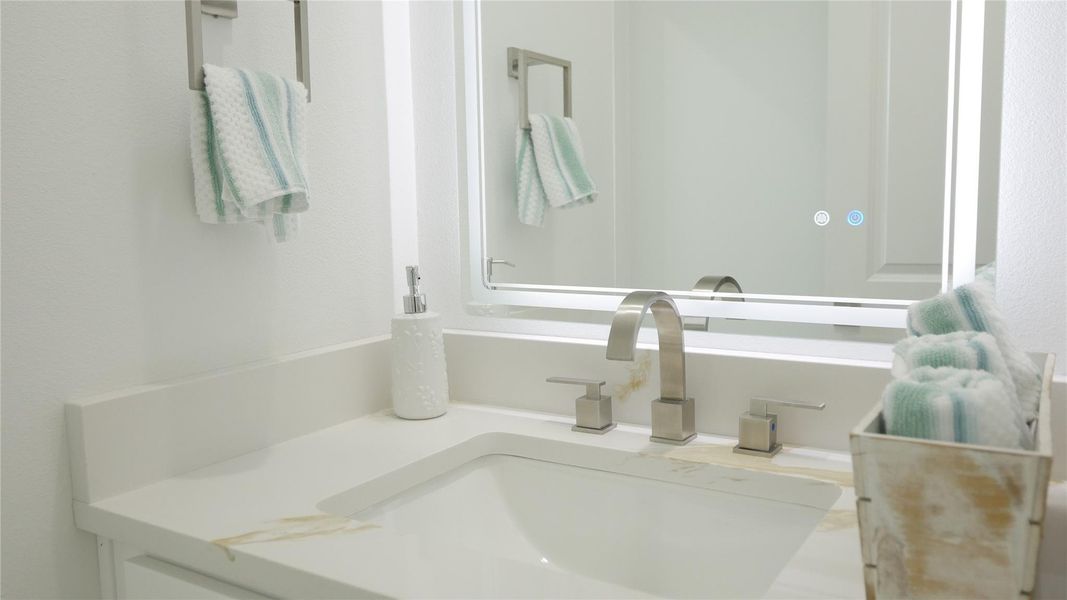 This bathroom features a modern design with a sleek white countertop, integrated sink, and stylish fixtures. A well-lit mirror and neatly arranged towels add a touch of elegance. This bathroom features a modern design with a sleek white countertop, integrated sink, and stylish fixtures. A well-lit mirror and neatly arranged towels add a touch of elegance.