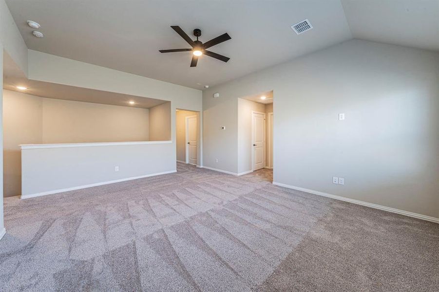 Spacious carpeted room featuring a vaulted ceiling with a ceiling fan, recessed lighting, and an open half-wall overlooking a lower level