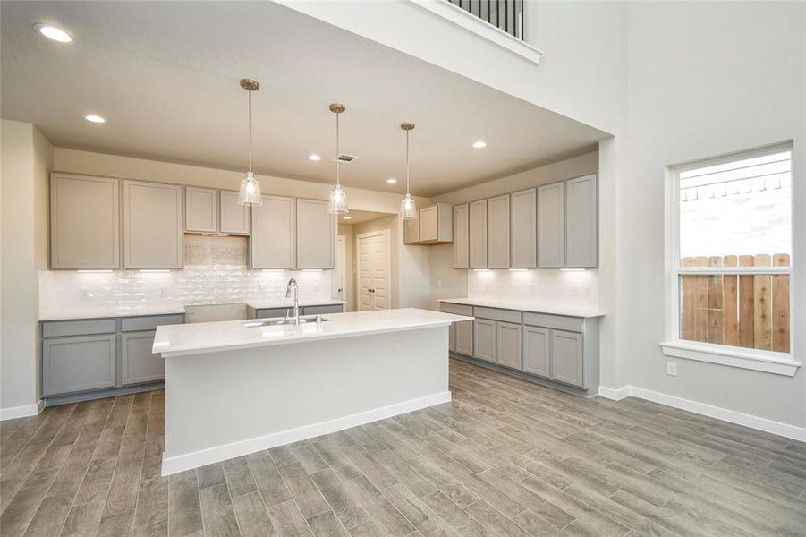 This generously spacious kitchen is a dream realized! With a massive granite island, high ceilings, soft close cabinets, granite countertops, stainless steel appliances (to be installed), a sleek tile backsplash, recessed and pendant lighting, it offers both style and practicality. All this opens up to the expansive family room, creating a perfect hub for gatherings. Sample photo of completed home with similar floor plan. Actual colors and selections may vary.