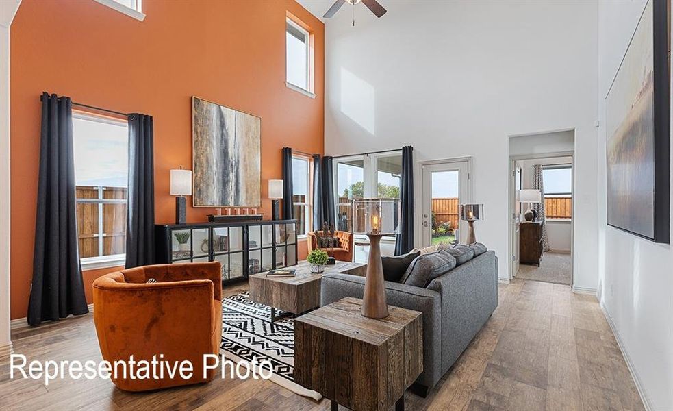 Open-concept living space featuring high ceilings, wood-finish flooring, and a glass-paneled back door